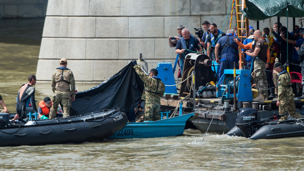 A hajóroncsból felhozott holttestet takarják el a kutatási munkálatokat végző szakemberek a balesetben elsüllyedt Hableány turistahajó közelében, a Margit hídnál kiépített pontonnál 2019. június 4-én. A Hableány és a Viking Sigyn szállodahajó május 29-én késő este ütközött össze a Margit híd közelében, a turistahajó felborult és elsüllyedt, fedélzetén 33 dél-koreai állampolgárral - turistákkal és két idegenvezetővel -, valamint kéttagú magyar személyzettel. Hét embert a környező hajókon utazók kimentettek, hét dél-koreai állampolgár holttestét pedig még aznap megtalálták. Június 4-éig tíz holttest került elő.