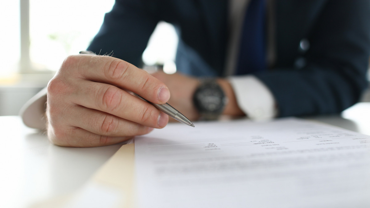 Mans hands in a business suit makes notes at the table. Businessman busy with professional career and self-interest