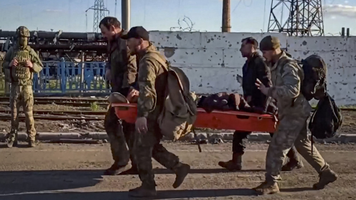 Az orosz védelmi minisztérium sajtószolgálata által videófelvételről készített képen ukrán katonák viszik sebesült társukat a mariupoli Azovsztal acélmű területén 2022. május 17-én. A nap folyamán több mint 260 ukrán harcos - sokan közülük sebesültek - hagyhatta el az acélmű területét.