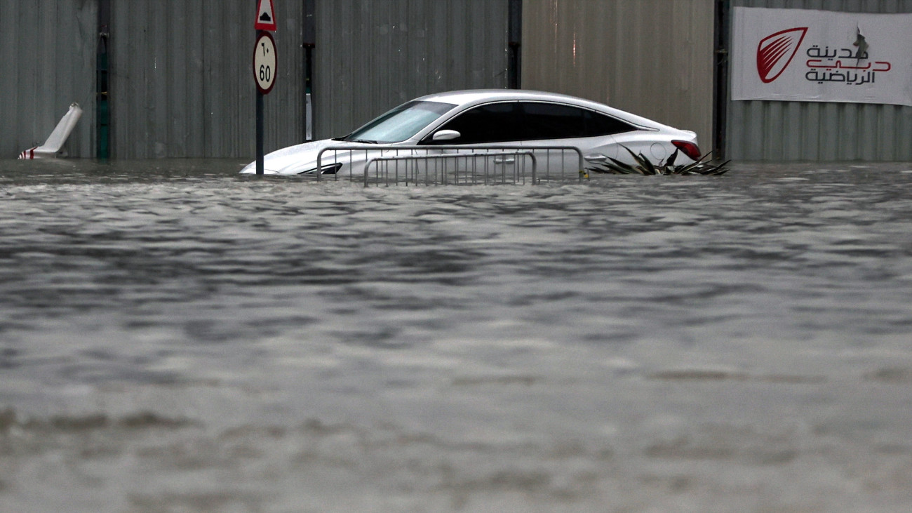 Vízben álló autó egy árvízzel elárasztott úton a heves esőzések sújtotta Dubajban 2024. április 16-án. A viharos időjárás miatt ideiglenesen más repülőterekre irányítják át az érkező gépeket a dubaji nemzetközi repülőtérről.