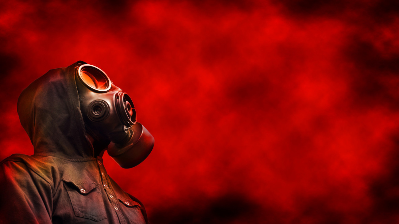 Person wearing hoody and gas mask with red toxic fumes