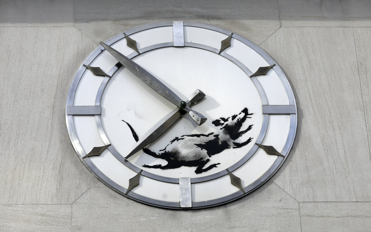 New York, 2018. március 16.
Banksy brit graffitiművész újabb alkotása egy patkányt ábrázol egy New York-i egykori banképület óráján, a14. utca és a 6. sugárút sarkán 2018. március 15-én. (MTI/EPA/Jason Szenes)