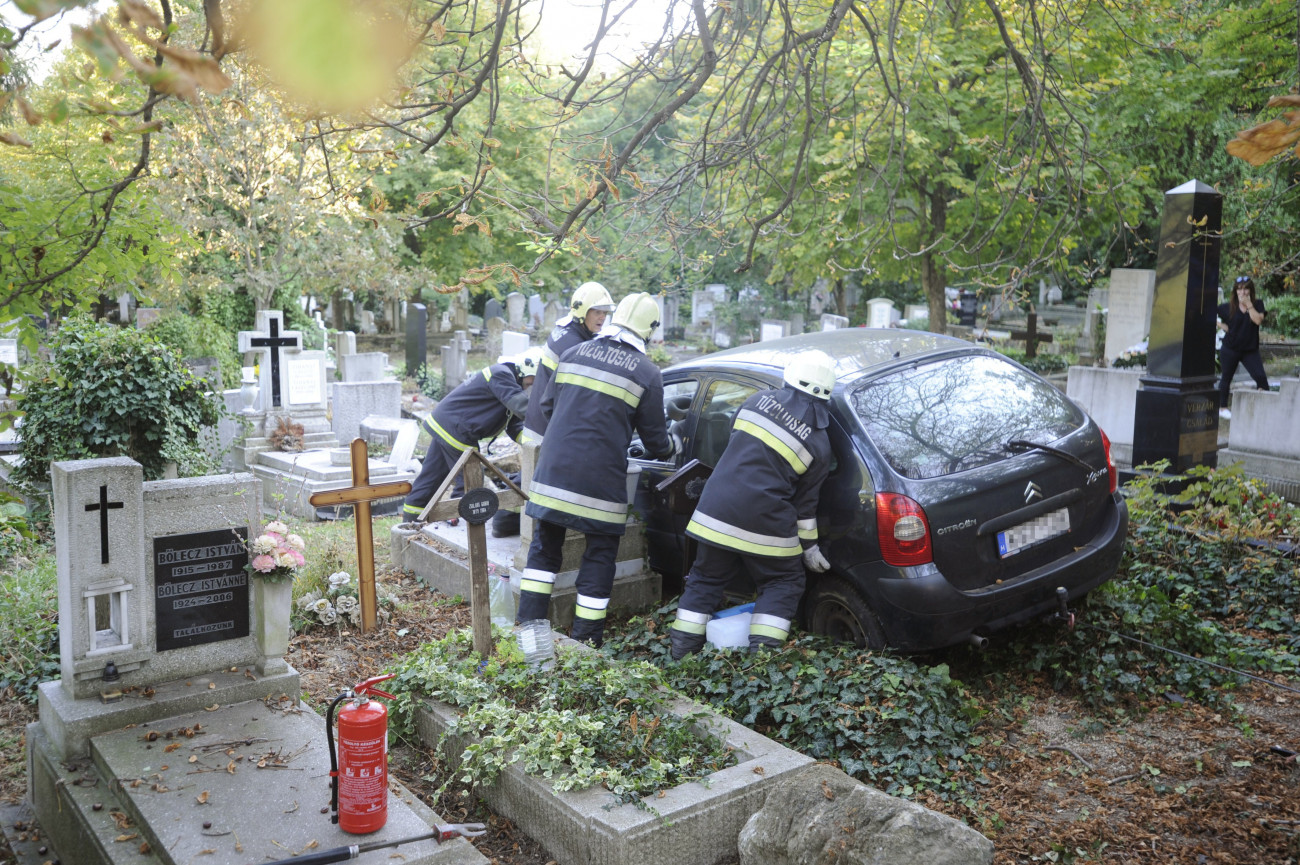 Budapest, 2018. október 9.
Tűzoltók dolgoznak egy személyautó műszaki mentésén a Farkasréti temetőben 2018. október 9-én. A jármű megcsúszott a temető melletti meredek úton, átszakította a temető kerítését, a sírok között állt meg, több sírt megrongálva. Személyi sérülés nem történt.
MTI Fotó: Mihádák Zoltán