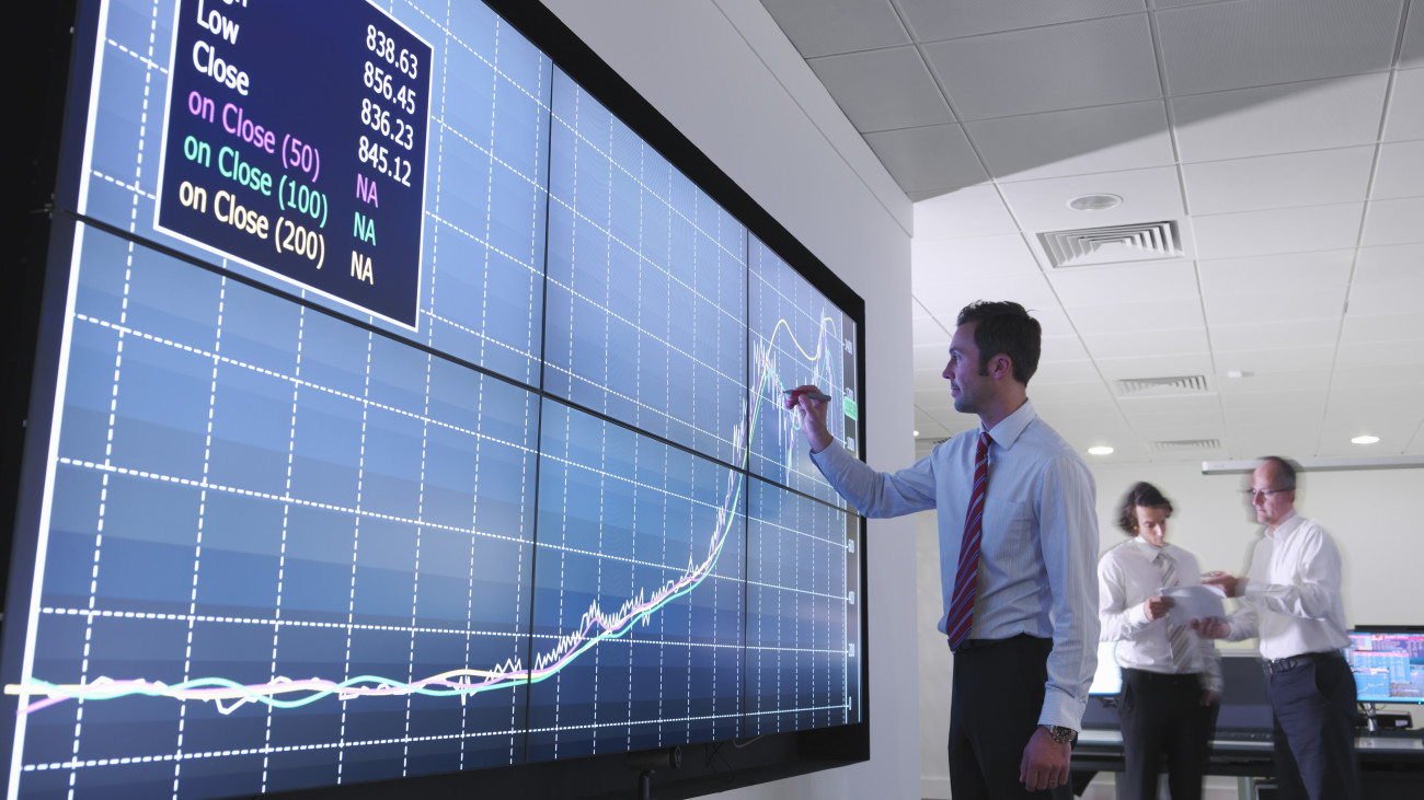 Low angle view of finance businessman writing on touchscreen graph in modern office