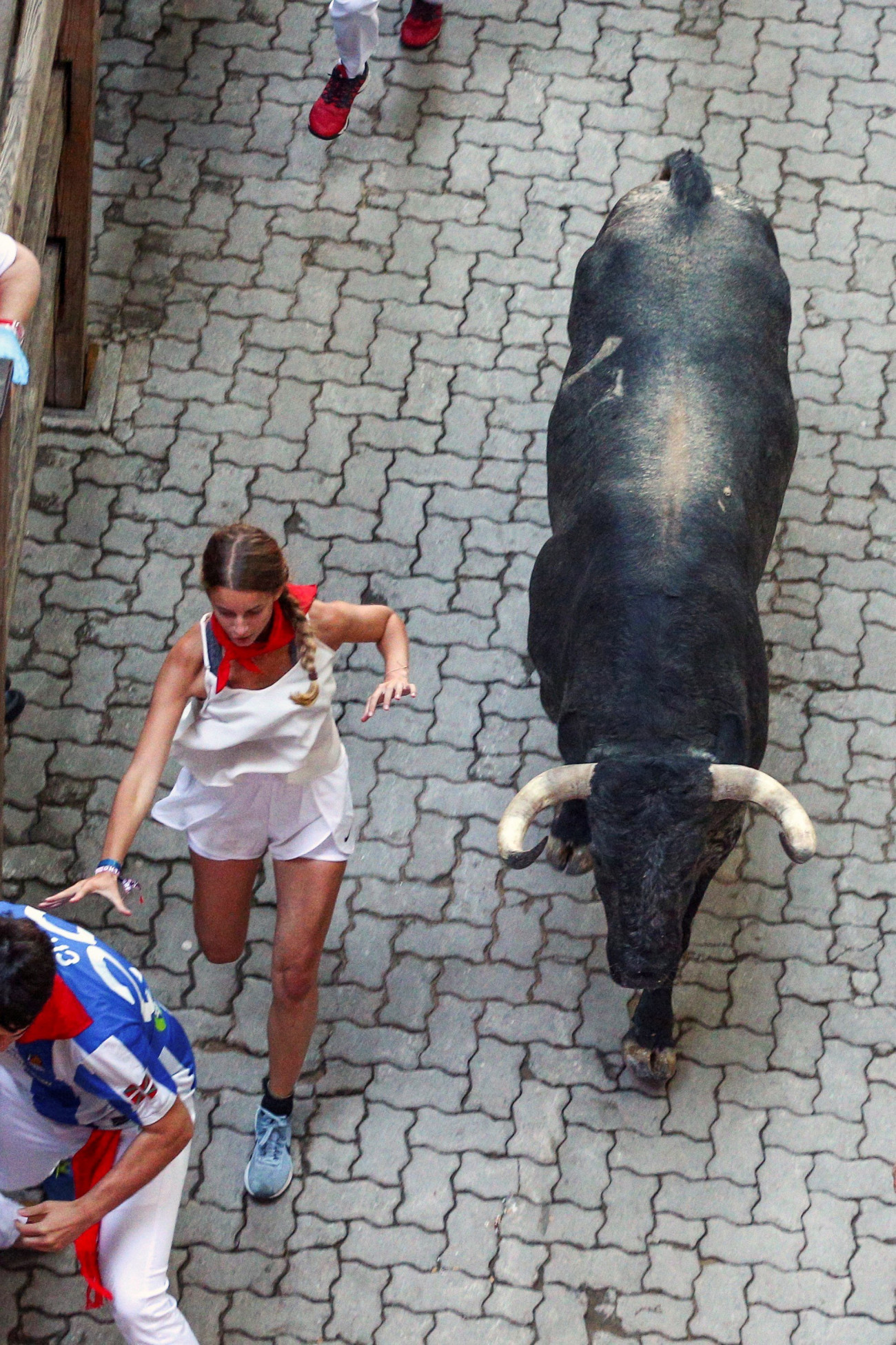 Pamplona, 2018. július 9.
Női résztvevő menekül egy bika elől a pamplonai San Fermín fesztivál harmadik napján, 2018. július 9-én. A spanyol város védőszentjének tiszteletére 1591 óta évente megrendezett kilencnapos fiesta egyik fő attrakciója a reggelenkénti bikafuttatás, amelynek során férfiak százai teszik próbára bátorságukat azzal, hogy az arénába hajtott állatok előtt végigszaladnak Pamplona utcáin. (MTI/EPA/Rodrigo Jiménez)