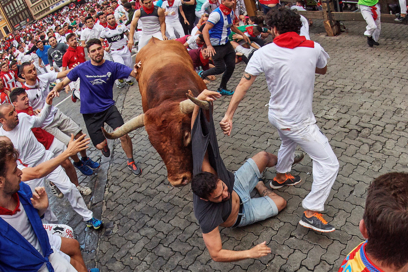 Felökleli a bika az egyik futót a San Fermín fesztiválon Pamplonában 2019. július 14-én. A spanyol város védőszentjének tiszteletére 1591 óta évente megrendezett kilencnapos fiesta egyik fő attrakciója a reggelenkénti bikafuttatás, amelynek során férfiak százai teszik próbára bátorságukat azzal, hogy az arénába hajtott állatok előtt végigszaladnak Pamplona utcáin.
MTI/EPA/Daniel Fernandez