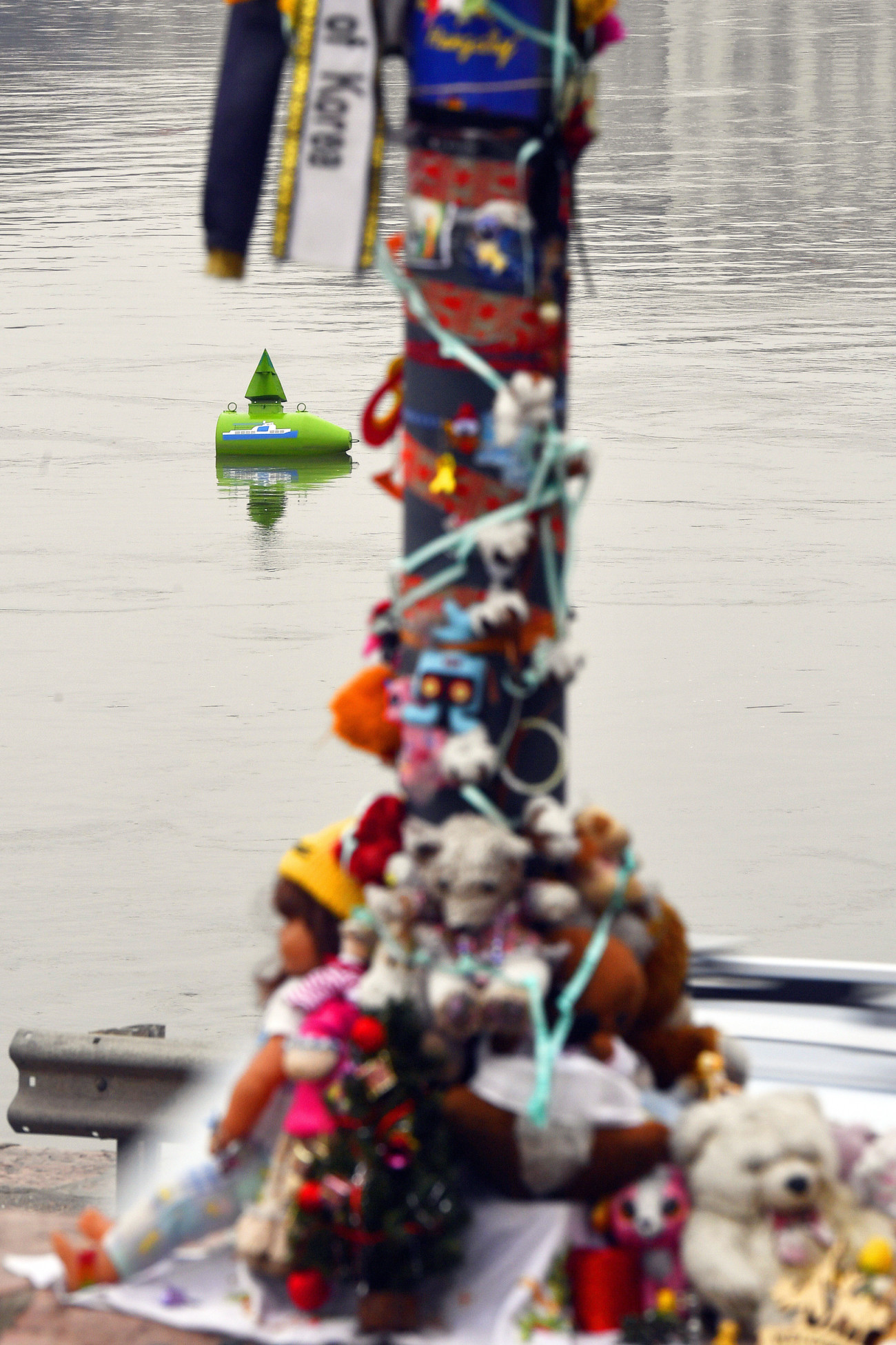 Budapest, 2020. január 3.
Az elsüllyedt Hableány sétahajó képe egy bóján a Margit híd közelében 2020. január 3-án. Előtérben az áldozatok emlékére elhelyezett játék figurák. A sétahajó 2019. május 29-én este a híd közelében merült el a vízben, miután összeütközött a Viking Sigyn szállodahajóval. A Hableányon 35-en utaztak, 33 dél-koreai turista és a kéttagú magyar személyzet. A balesetet követően hét dél-koreait sikerült kimenteni, és azóta huszonhét holttestet találtak meg.
MTI/Máthé Zoltán