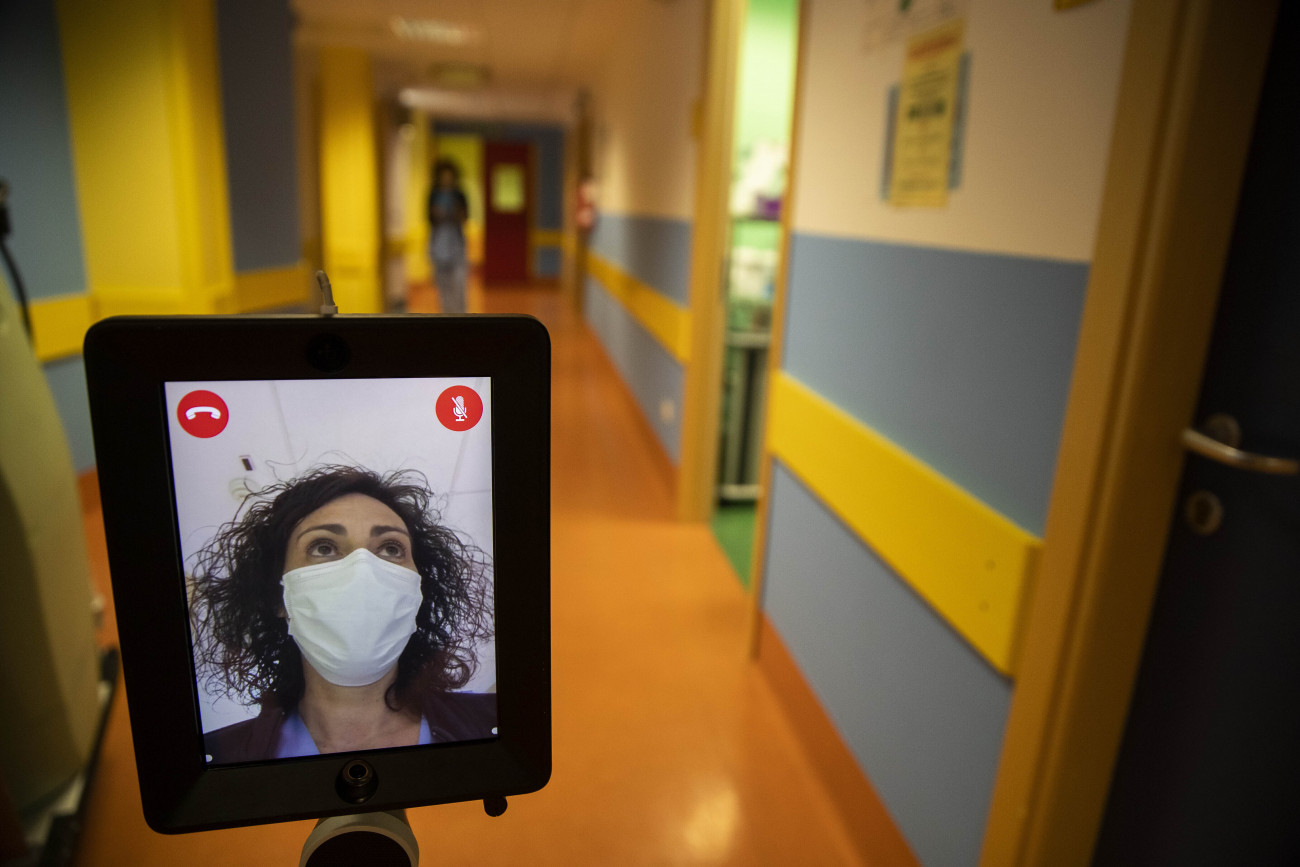 Varese, 2020. április 8.
Görgőkkel ellátott szerkezetre felszerelt tabletet irányít távolról, okostelefon segítségével egy ápolónő az olaszországi Varese egyik kórházában 2020. április 8-án. Az Ivo elnevezésű eszköz be tud menni a betegek szobájába, így a dolgozók videohívás útján tudnak kommunikálni velük.
MTI/AP/Luca Bruno