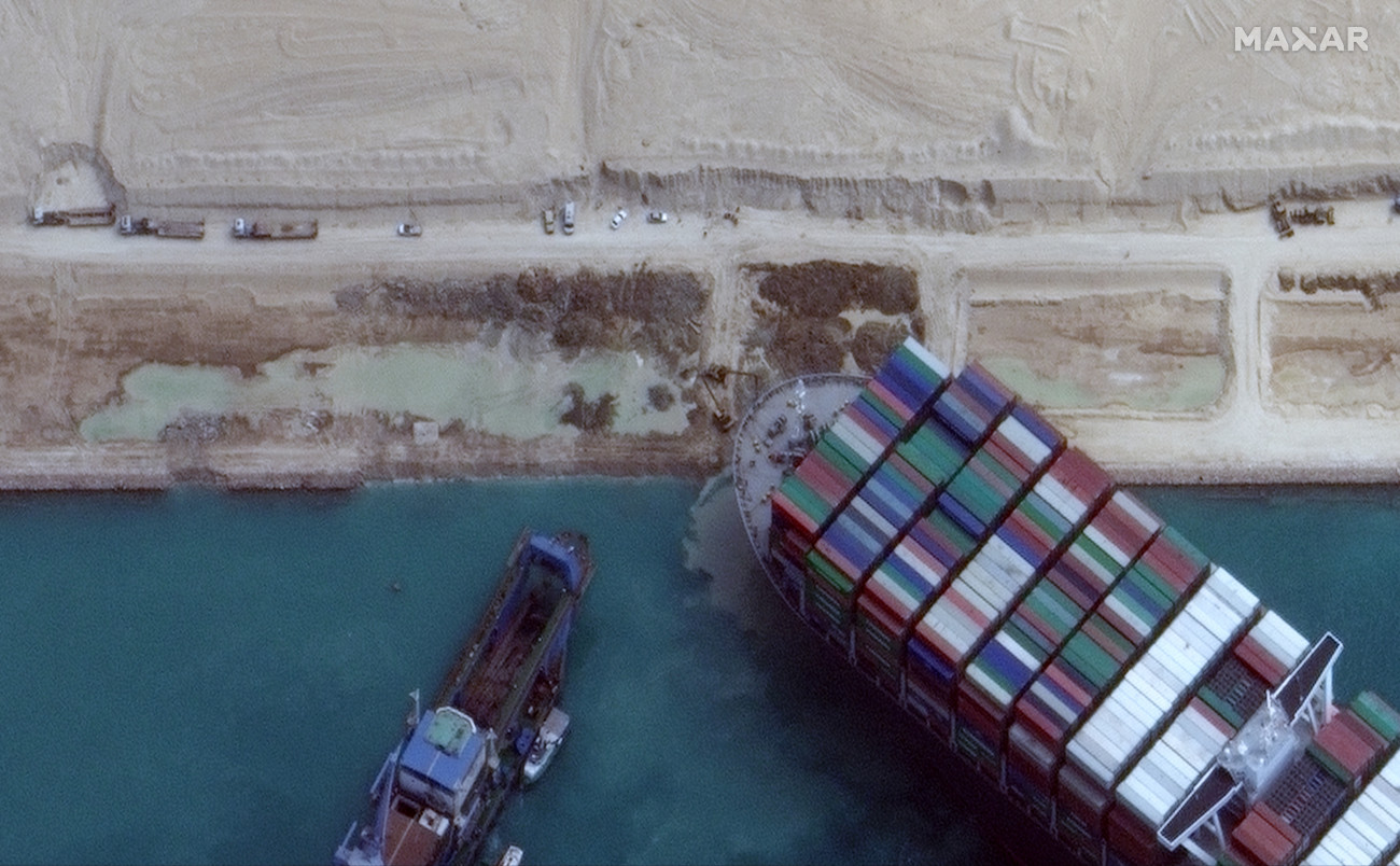 Szuezi-csatorna, 2021. március 28.
A Maxar Technologies által közreadott műholdfelvételen munkagépekkel és vontatóhajókkal próbálják kiszabadítani a keresztbe fordult és beszorult Ever Given nevű konténerszállítót a Szuezi-csatornában 2021. március 28-án. A világ egyik legnagyobb teherhajója öt napja blokkolja a forgalmat, a baleset miatt felfüggesztették a hajóforgalmat a Szuezi-csatornában.
MTI/EPA/Maxar Technologies