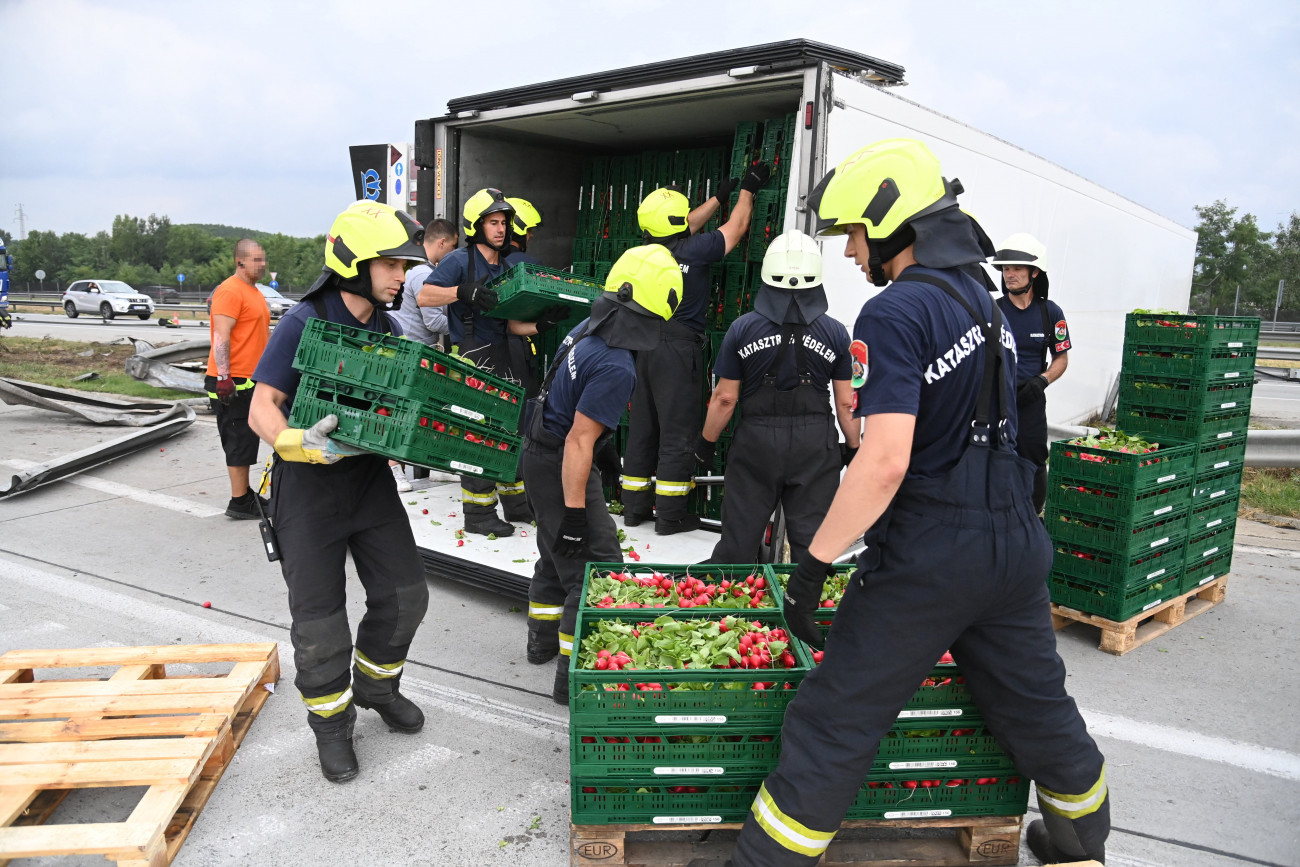 Gyál, 2021. augusztus 5.
A műszaki mentéshez tűzoltók pakolják ki egy tisztázatlan okból felborult román rendszámú kamion rakományának egy részét az M0-ás autóút M5-ös autópálya felé vezető oldalán, Gyál közelében 2021. augusztus 5-én.
MTI/Mihádák Zoltán