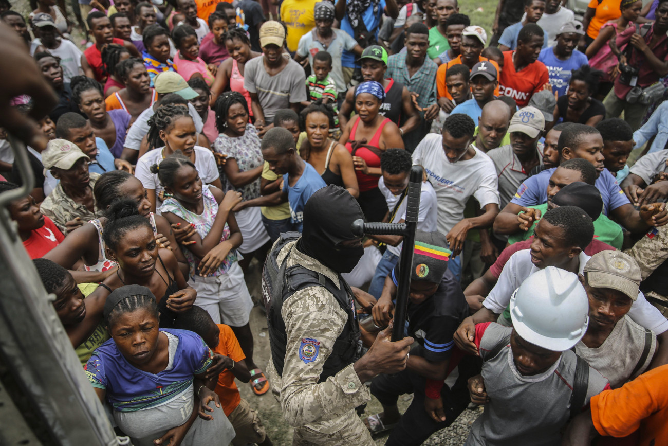 Les Cayes, 2021. augusztus 17.
Rendőr próbálja helyreállítani a rendet az élelmiszersegélyre váró emberek között Haiti Les Cayes nevű településén 2021. augusztus 16-án, két nappal a karibi szigetország délnyugati részét megrázó, 7,2-es erősségű földrengés után. Az állami televízió augusztus 17-i tájékoztatása szerint 6900 sérültet és 1419 halálesetet tartanak nyilván.
MTI/AP/Joseph Odelyn