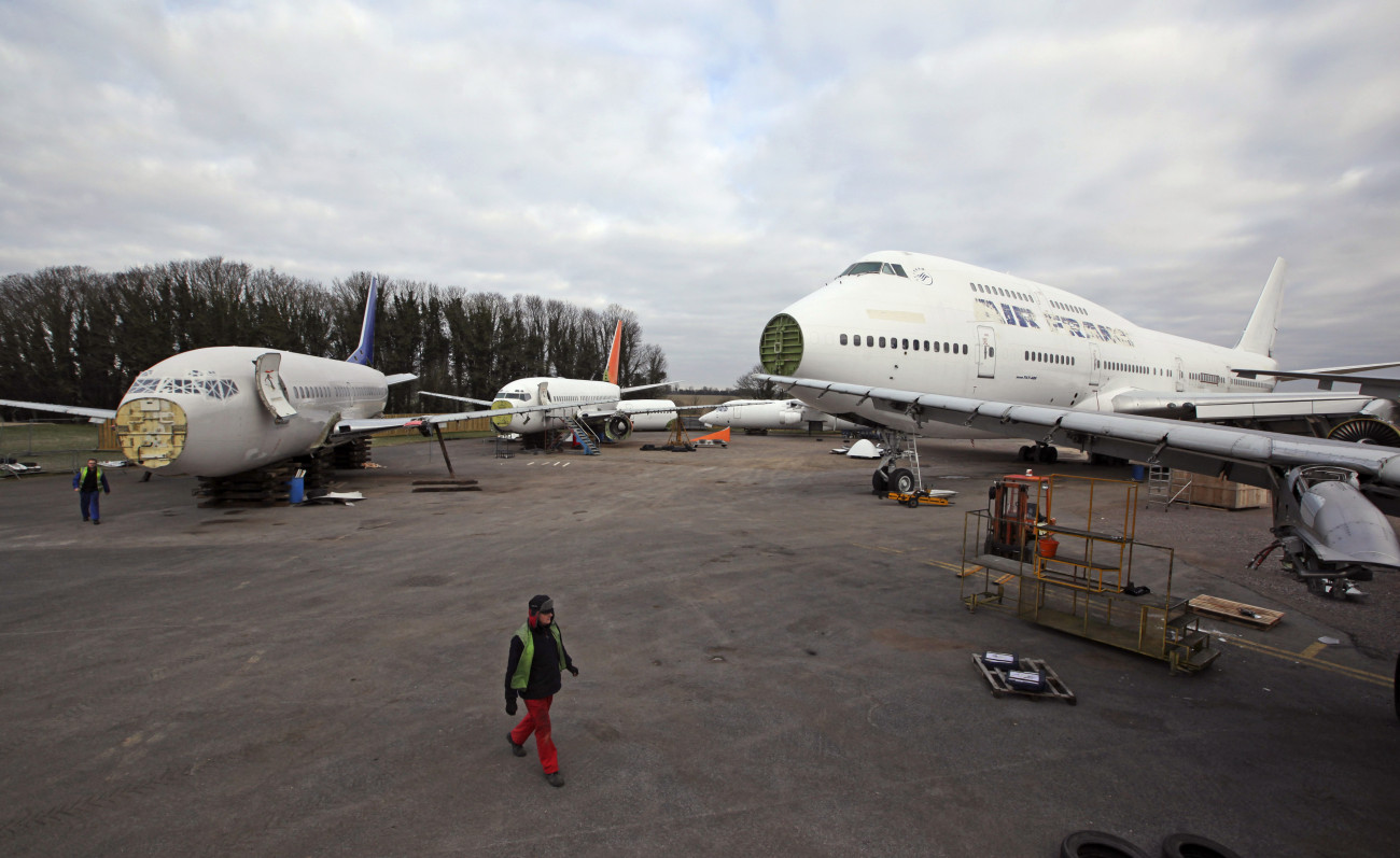 An employee passes partially dismantled aircraft, including a Boeing 747-400 formerly operated by Air France SA, as he crosses the yard of Air Salvage International Ltd. at Kemble airfield near Cirencester, U.K., on Friday, Feb. 3, 2012. Disused aircraft generate new money for U.K. airplane salvage company Air Salvage International Ltd. based in Gloucestershire. Photographer: Chris Ratcliffe/Bloomberg via Getty Images