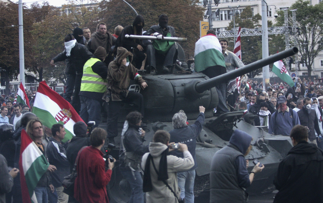 BUDAPEST, HUNGARY - OCTOBER 23:  Demonstrators driving a 1950s-era tank they commandeered drive through other massed demonstrators on their way to charging a police cordon during violent street protests on October 23, 2006 in Budapest, Hungary. The country is officially commemorating the 50th anniversary of its bloody uprising against Soviet occupation in 1956, though protests turned violent in the afternoon as demonstrators sought to reach the Parliament building. Police fired water cannons, tear gas and rubber bullets at tens of thousands of demonstrators. Many Hungarians are angry that Prime Minister Ferenc Gyurcsany has not stepped down, even though he was recorded admitting that he had lied extensively to the Hungarian public prior to recent elections.  (Photo by Sean Gallup/Getty Images)