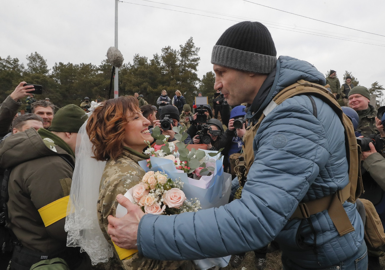 Kijev, 2022. március 6.
A kijevi polgármester, Vitalij Klicsko egykori nehézsúlyú profi ökölvívó (j) gratulál házasságkötésük után Valerijnak és Leszjának (b), az ukrán területvédelmi alakulatok két tagjának egy Kijev melletti támaszponton 2022. március 6-án. Vlagyimir Putyin orosz elnök február 24-én rendelte el katonai művelet végrehajtását Ukrajnában.
MTI/EPA/Szerhij Dolzsenko