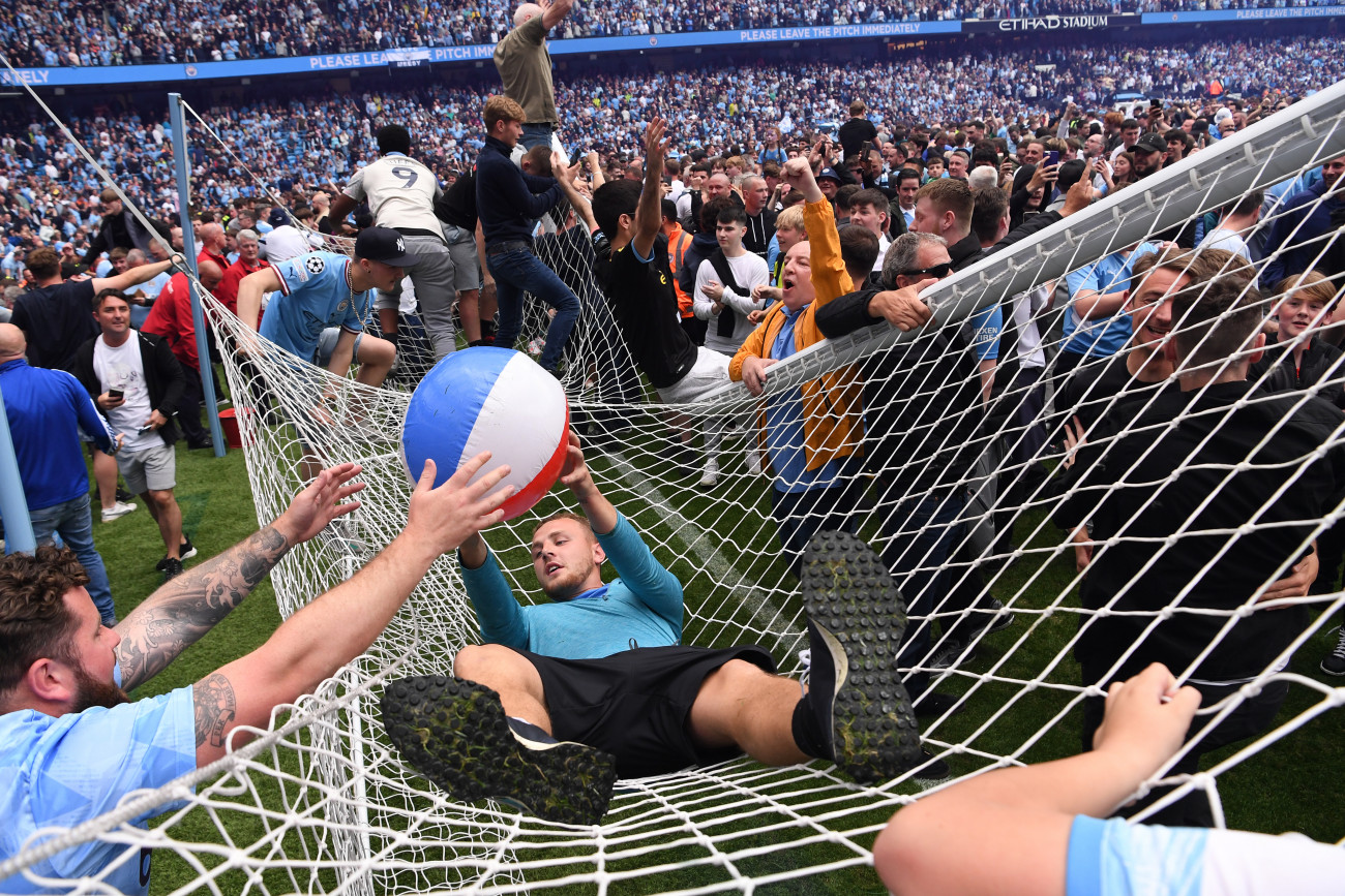 MANCHESTER, ENGLAND - MAY 22: Manchester City fans celebrate winning the Premier League title on the pitch by  climbing onto the roof of the net as the crossbar snaps after the Premier League match between Manchester City and Aston Villa at Etihad Stadium on May 22, 2022 in Manchester, England. (Photo by Stu Forster/Getty Images)