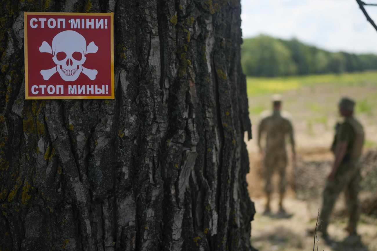 Kijev, 2022. június 9.
Aknamezőre figyelmeztető tábla közelében dolgozik egy ukrán aknamentesítő különítmény Kijev térségében 2022. június 9-én.
MTI/AP/Natacha Pisarenko
