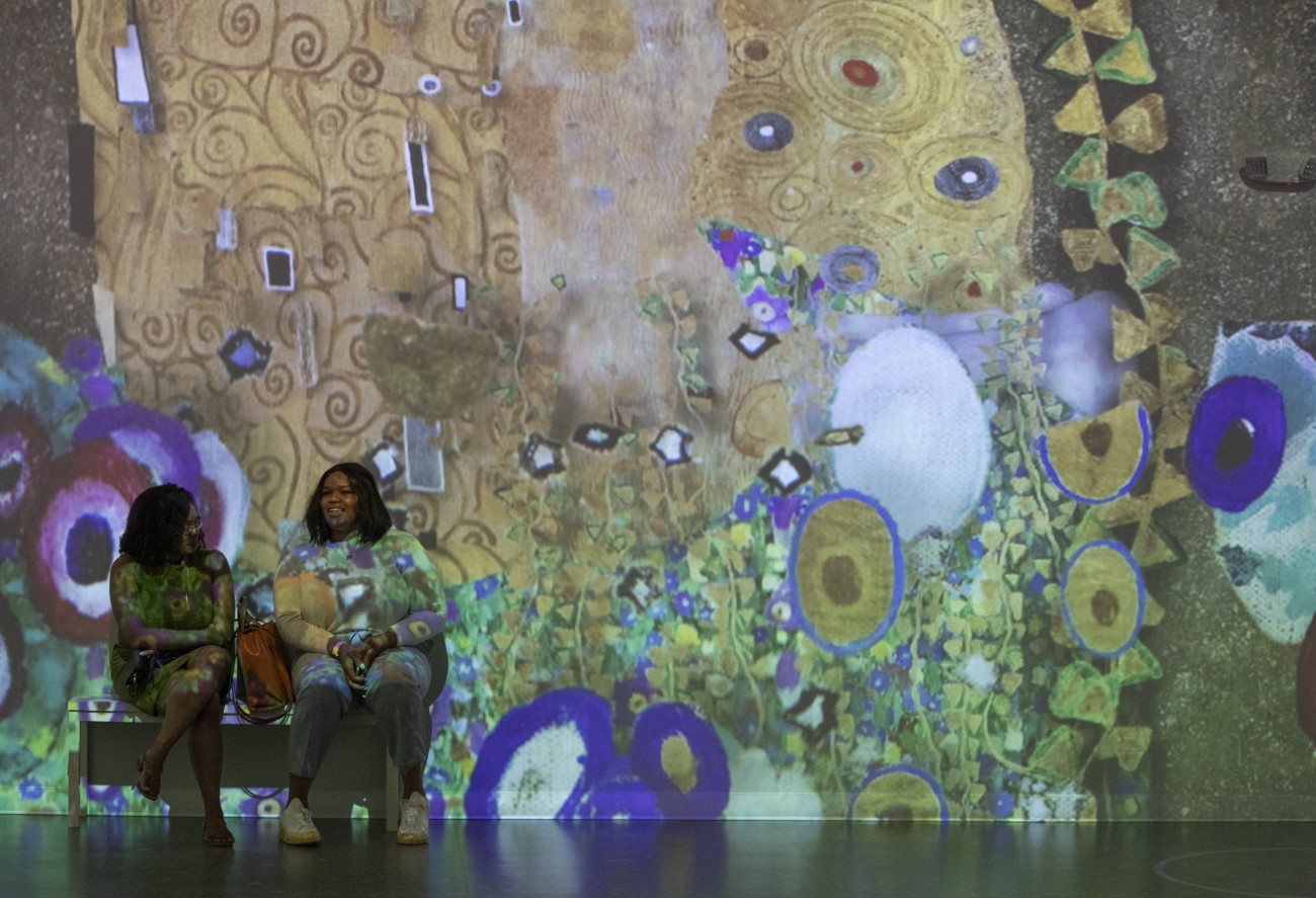 Boston, 2022. április 14.
Látogatók a Gustav Klimt osztrák festőművész (1862-1918) alkotásaiból nyílt digitális  művészeti kiállításon Bostonban 2022. április 14-én. A kiállítótermekben projektor vetíti a padlóra, a mennyezetre és a falakra Klimt alkotásait térbeli hangosítás mellett. A különleges élményt és látványt egyedi multimédiás eszközök biztosítják a tárlaton.
MTI/EPA/C. J. Gunther