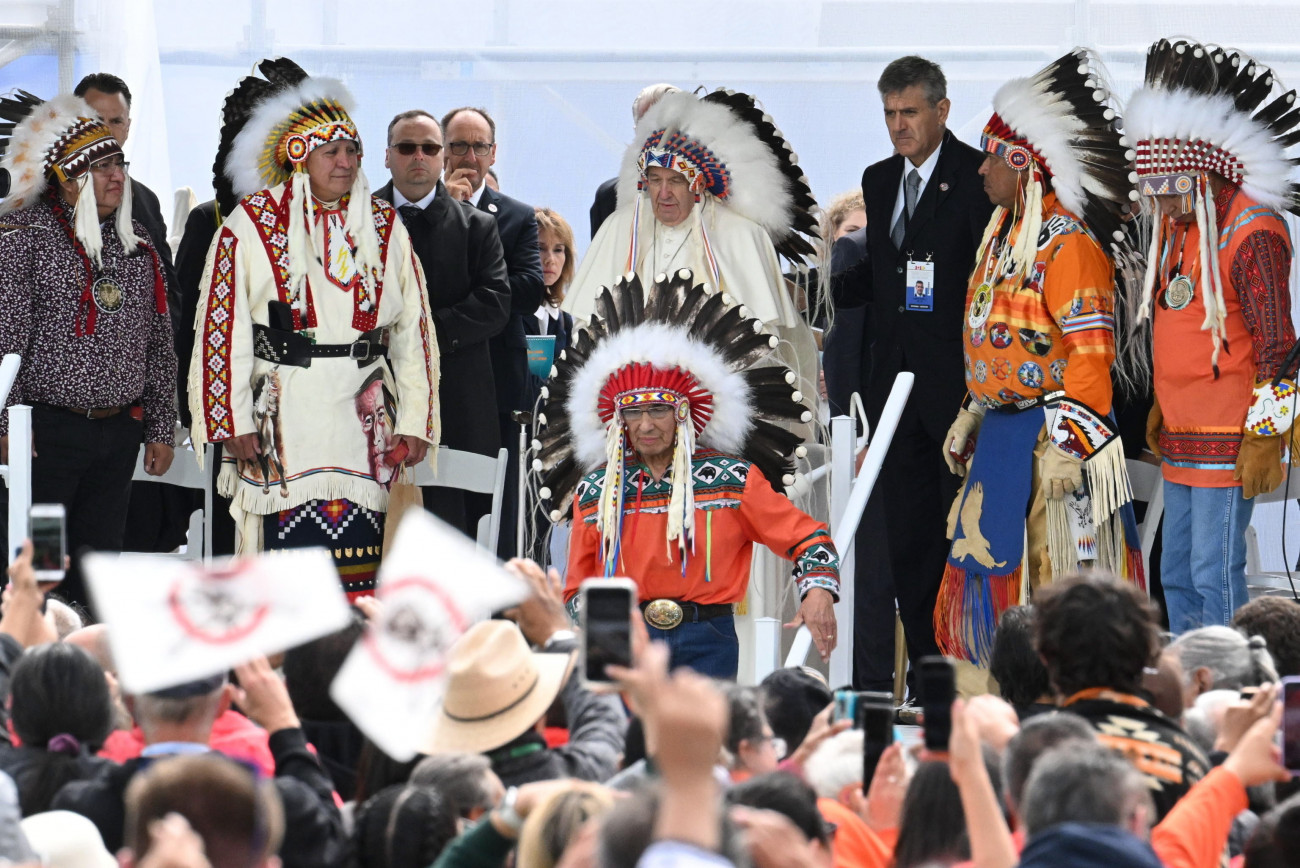 Maskwacis, 2022. július 25.
Ferenc pápa (k) hagyományos indián fejdíszt visel, amikor őslakosokkal találkozik a maskwacisi temetőben rendezett közös imán 2022. július 25-én.
MTI/EPA/ANSA/Ciro Fusco