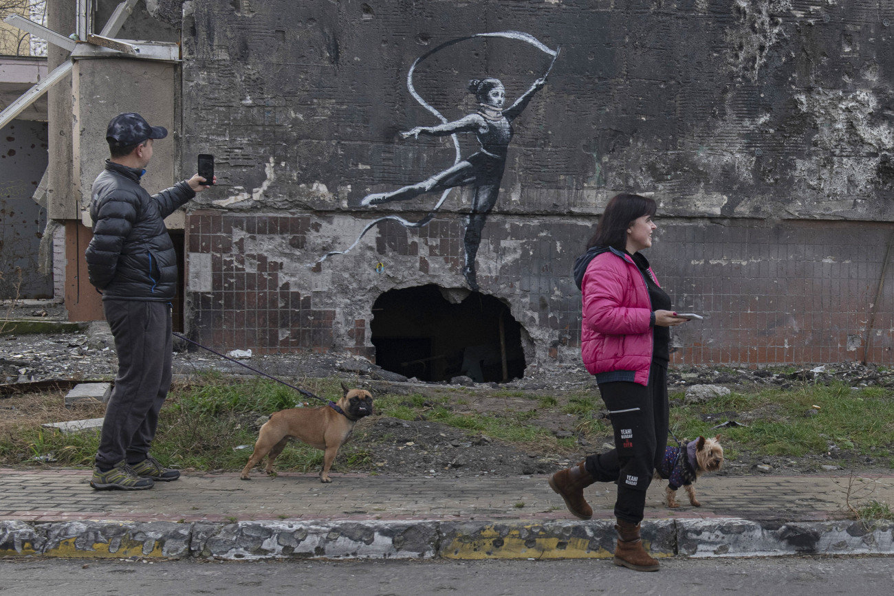 Irpiny, 2022. november 13.
Fényképet készít egy férfi a háború során megrongálódott épület egyik falára festett alkotásról a Kijev közelében fekvő Irpinyben 2022. november 13-án. Afalfestményt feltehetően Banksy brit graffitiművész készítette.
MTI/AP/Andrew Kravchenko