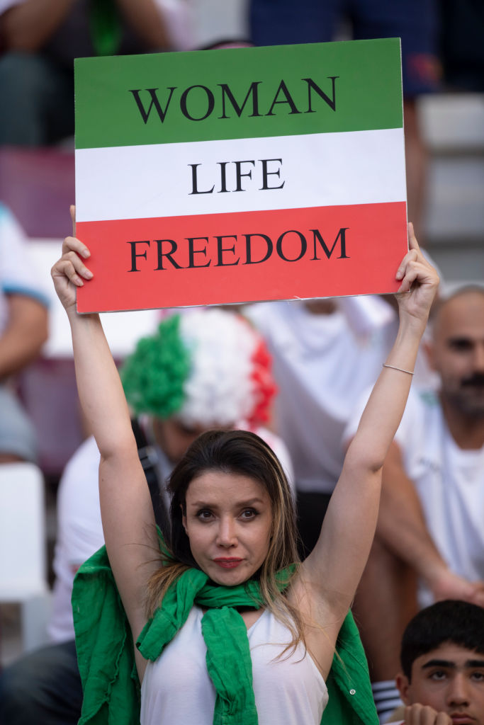DOHA, QATAR - NOVEMBER 21: A fan holds up an Iran sign reading WOMAN LIFE FREEDOM to show solidarity with the women's protest movement in Iran during the FIFA World Cup Qatar 2022 Group B match between England and IR Iran at Khalifa International Stadium on November 21, 2022 in Doha, Qatar. (Photo by Visionhaus/Getty Images)
