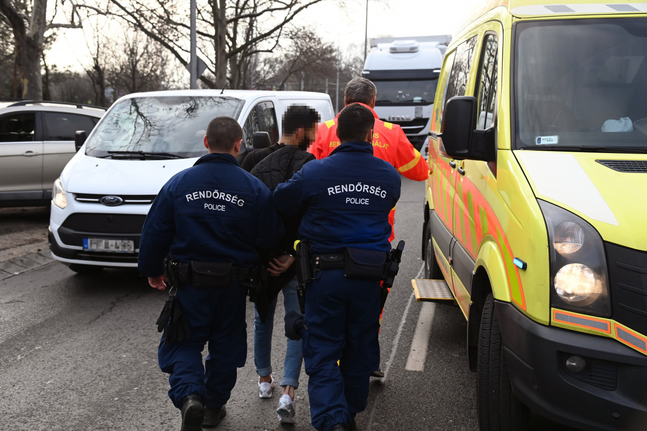 Budapest, 2023. január 12.
Rendőrök elvezetnek egy férfit, akit elfogtak Budapesten, a IX. kerületben 2023. január 12-én. A rendőrök elől menekülő autós két parkoló autónak, majd villanyoszlopnak ütközött. Az Epreserdő utcában oszlopnak csapódó autóba hajtott a mögötte haladó járőrautó is. Kőbányai rendőrök igazoltatni akarták a személygépkocsi vezetőjét a X. kerületi Száva utcában, mert arról érkezett bejelentés, hogy a férfi egy nőt üldöz. Az autós a rendőri jelzést figyelmen kívül hagyva elhajtott, a rendőrök fényjelzést és szirénát használva követték.
MTI/Mihádák Zoltán