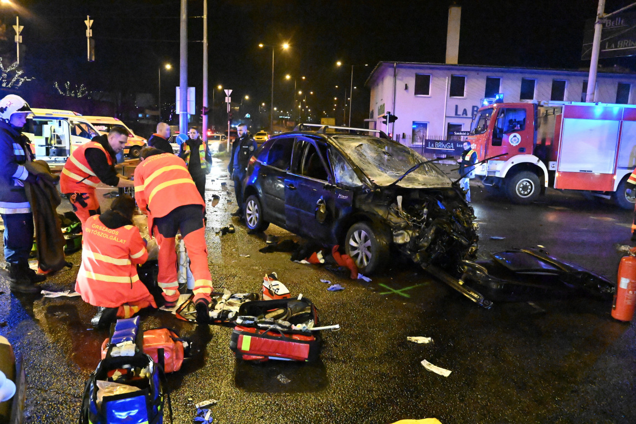 Budapest, 2023. január 16. 
Mentők sérültet ápolnak összeroncsolódott személygépkocsi mellett a IX. kerületi Soroksári út és a Kvassay Jenő út kereszteződésében, ahol a gépjármű és egy nyerges vontató ütközött 2023. január 15-én. A balesetben egy ember meghalt, három pedig megsérült.
MTI/Mihádák Zoltán