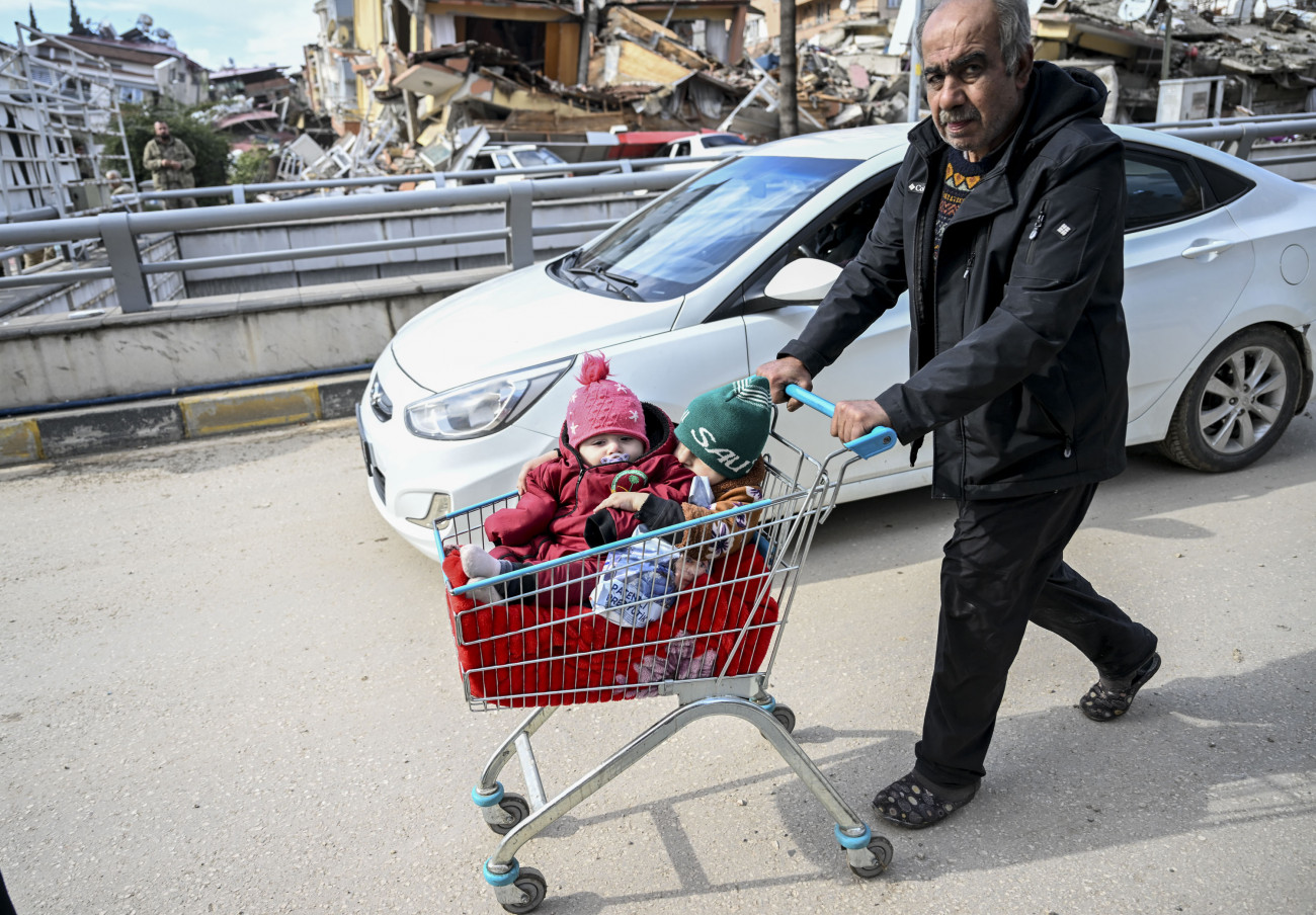 HATAY, TURKIYE - FEBRUARY 07: A man carry children in a shopping cart after 7.7 and 7.6 magnitude earthquakes hit Hatay, Turkiye on February 07, 2023. Early Monday morning, a strong 7.7 earthquake, centered in the Pazarcik district, jolted Kahramanmaras and strongly shook several provinces, including Gaziantep, Sanliurfa, Diyarbakir, Adana, Adiyaman, Malatya, Osmaniye, Hatay, and Kilis. Later, at 13.24 p.m. (1024GMT), a 7.6 magnitude quake centered in Kahramanmaras' Elbistan district struck the region. Turkiye declared 7 days of national mourning after deadly earthquakes in southern provinces. (Photo by Ercin Erturk/Anadolu Agency via Getty Images)