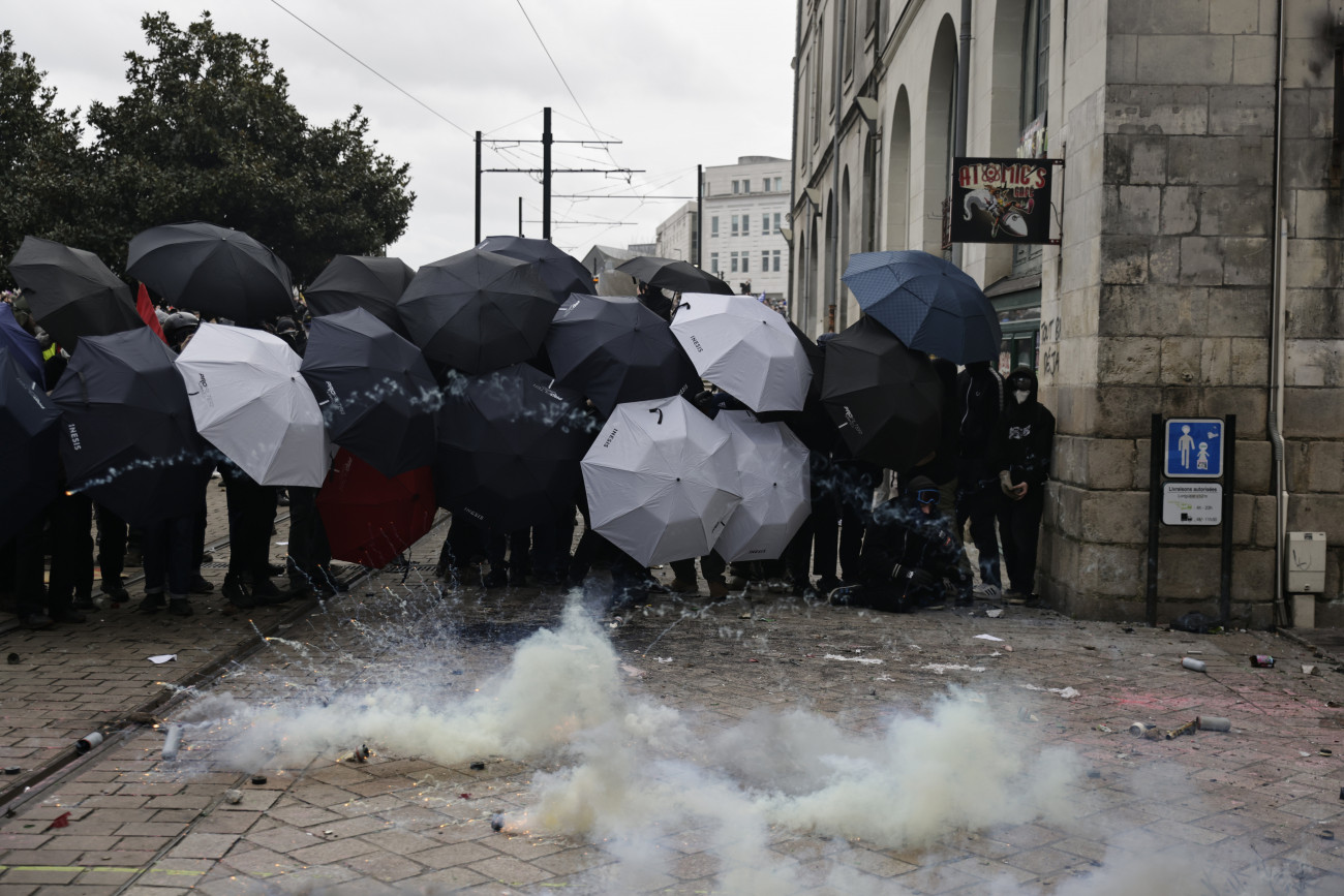 Nantes, 2023. március 23.
A nyugdíjreform ellen tüntetők esernyővel védekeznek a könnygáz ellen, amint összecsapnak a rohamrendőrökkel a nyugat-franciaországi Nantes-ban a francia szakszervezetek által meghirdetett egynapos országos sztrájk alatt, 2023. március 23-án. Emmanuel Macron elnök széles körű felháborodást váltott ki azzal, hogy parlamenti szavazás nélkül készül hatályba léptetni a nyugdíjkorhatár 62-ről 64 évre emelését előirányzó törvényt.
MTI/AP/Jeremias Gonzalez