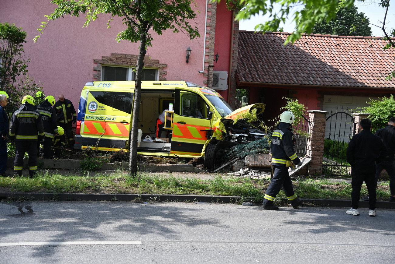 Budapest, 2023. május 17.
Egy ház kertjébe sodródott, összetört mentőautó az Újhegyi út és Mádi utca kereszteződésénél 2023. május 17-én. Személygépkocsi ütközött a mentőautóval, a balesetben senki nem sérült meg.
MTI/Mihádák Zoltán