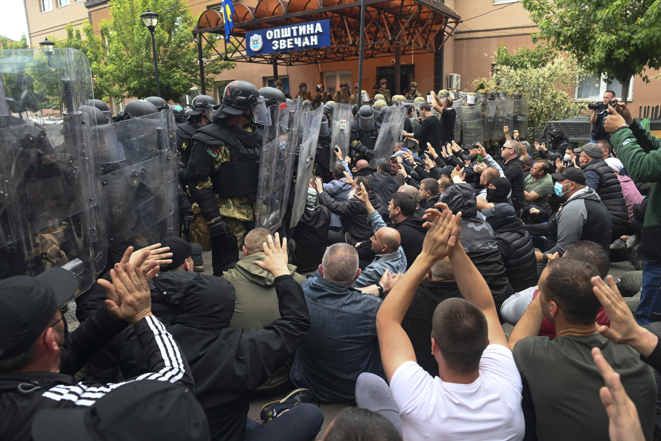Helyi szerbek ülnek az utcán a NATO parancsnoksága alatt működő koszovói békefenntartó haderő, a KFOR katonáinak sorfalával szemben a polgármesteri hivatal épülete előtt az észak-koszovói Zvecanban 2023. május 29-én. A szerbek tiltakozása május 26-án kezdődött, amikor Zvecan, Leposavic és Zubin Potok újonnan megválasztott, albán nemzetiségű polgármesterei megpróbálták elfoglalni hivatalaikat, de a helyi szerbek nem akarták beengedni őket az önkormányzati épületekbe.
MTI/EPA/Georgi Licovszki