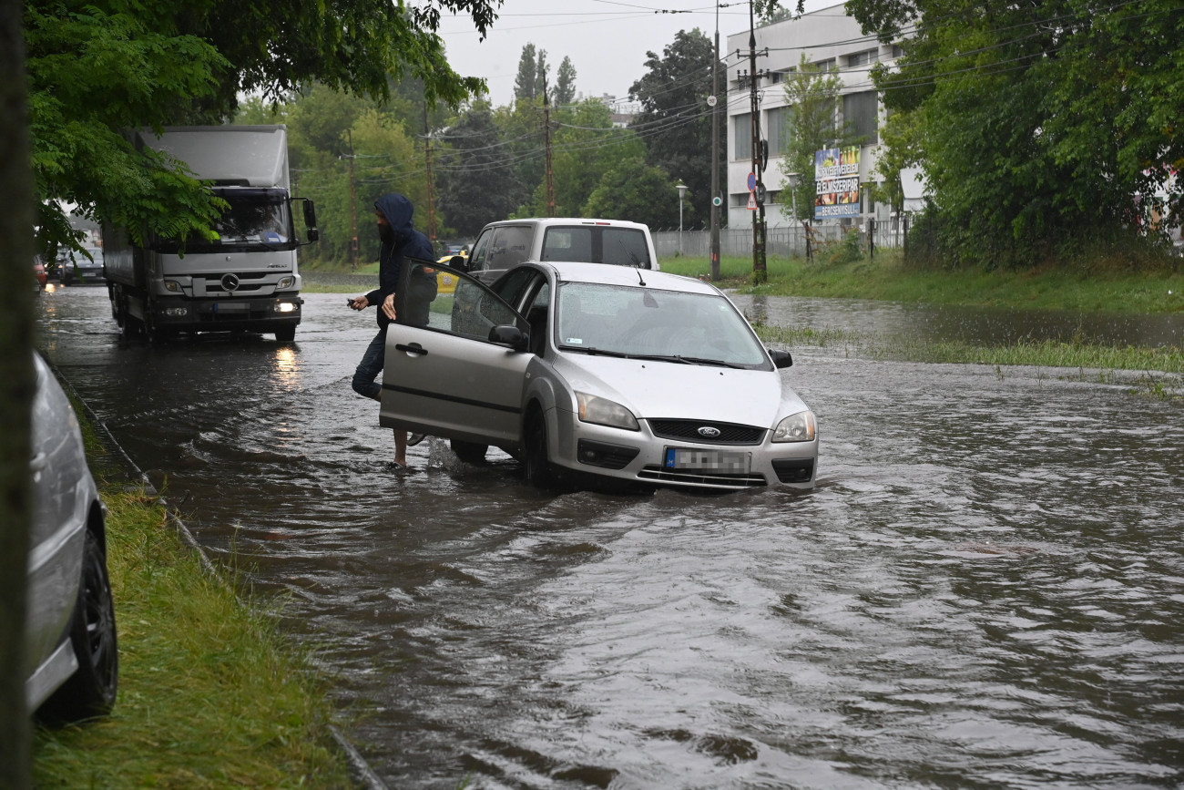 Budapest, 2023. június 9.
A felgyülemlett esővíztől elmozdult csatornafedél miatt a vízelvezetőben elakadt személygépkocsi a Maglódi úton 2023. június 9-én.
MTI/Mihádák Zoltán