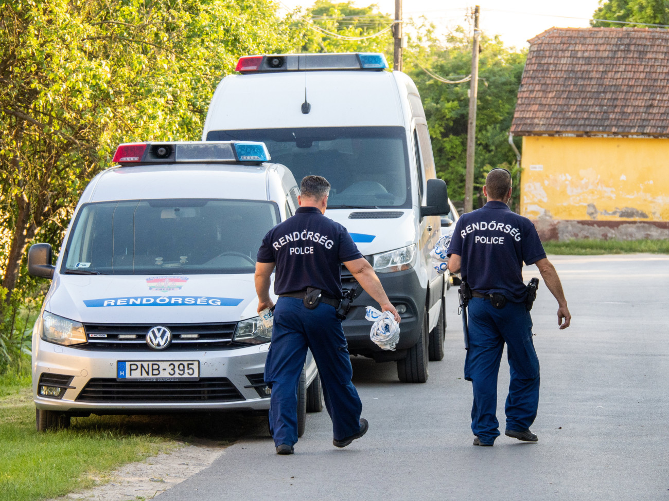 Jánoshalma, 2023. június 19.
Rendőrök és rendőrautók 2023. június 18-án Jánoshalmán, ahol holtan találtak egy idős nőt. A 80 éves áldozatra az ágyában talált rá a szomszédja június 18-án hajnalban. A nő meggyilkolásával egy 23 éves férfit gyanúsítanak, akit a rendőrök őrizetbe vettek és kezdeményezték a letartóztatását.
MTI/Donka Ferenc