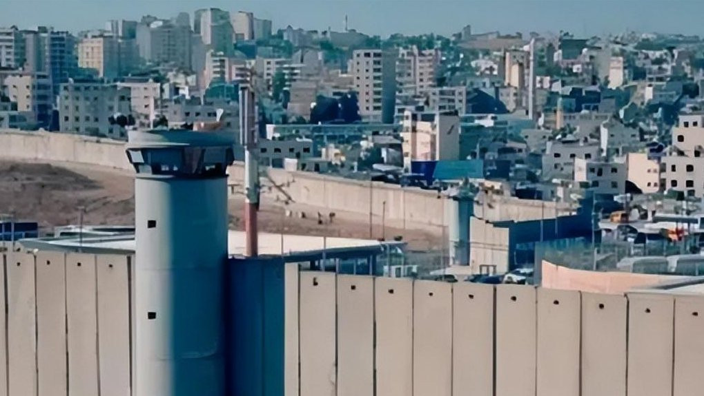 A Gázai-övezetet Izraeltől elválasztó, 8 méter magas és 2 méter vastag betonfal, valamint a határt figyelő egyik szenzortorony. Forrás: X /  Ansel·Weidel