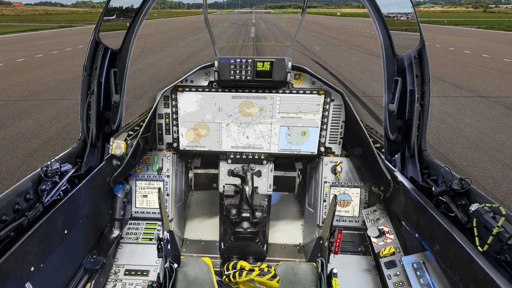 A Gripen legujabb E változatának pilóta fülkéje. A korábbi három kijelzőt egyetlen hatalmas képernyő váltotta fel. Forrás: SAAB