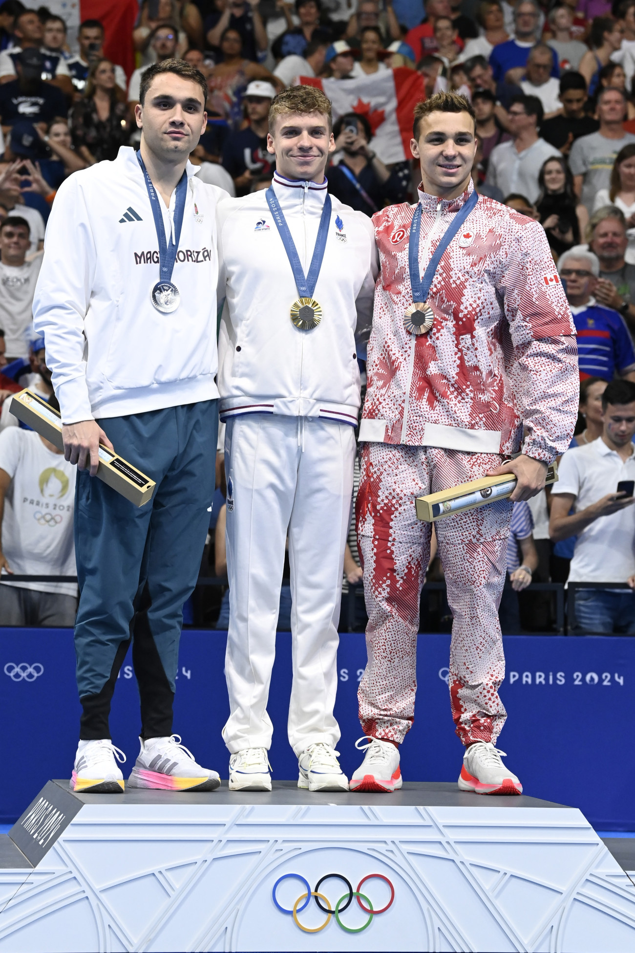 Nanterre, 2024. július 31.
Az aranyérmes francia Léon Marchand (k), az ezüstérmes Milák Kristóf (b) és a bronzérmes kanadai Ilya Kharun (j) a férfi 200 méteres pillangóúszás eredményhirdetésén a 2024-es párizsi nyári olimpián a Párizs melletti Nanterre-ben lévő Paris La Défense Arénában 2024. július 31-én.
MTI/Kovács Tamás