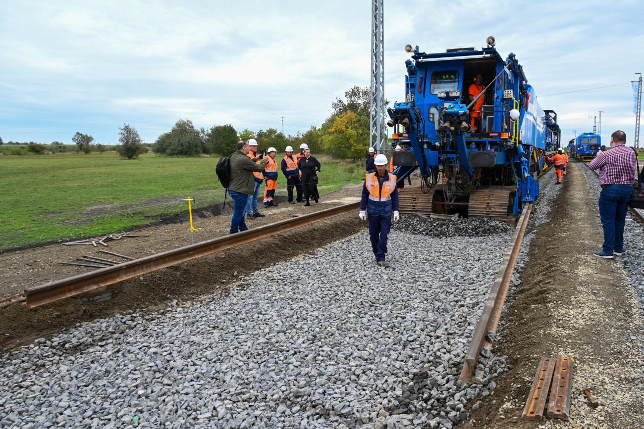 Kiskőrös, 2024. október 9.
Plasser & Theurer SMD 80 vágányfeketető gép a V-Híd gépbemutatóján, amelyen a Budapest-Belgrád vasútvonal nyíltvonali szakaszának utolsó vágánydarabját helyezték be Kiskőrösön 2024. október 9-én. Az eseményhez kapcsolódó ünnepségen Szijjártó Péter külgazdasági és külügyminiszter bejelentette, hogy az eddigi legfontosabb mérföldkövéhez ért az új Budapest-Belgrád vasútvonal építése, hiszen az utolsó sínszál lefektetésével a fővároson kívüli szakasz nyíltvonali vágányépítési munkálatai lezárultak, s így a jövő év végére elkészülhetnek a magyarországi munkálatok.
MTI/Máthé Zoltán