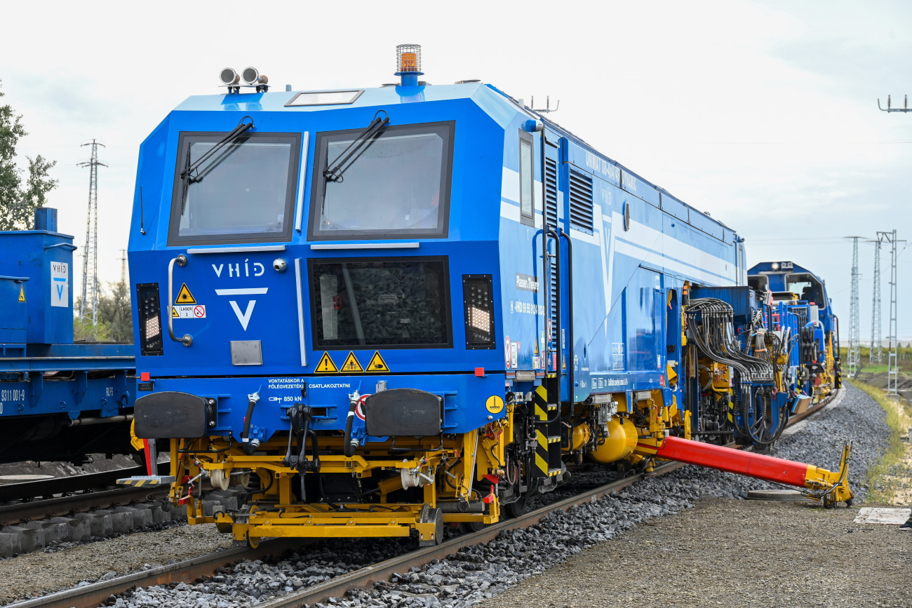 Kiskőrös, 2024. október 9.
Plasser & Theurer unimat 80 vágányszabályozó gép a V-Híd gépbemutatóján, amelyen a Budapest-Belgrád vasútvonal nyíltvonali szakaszának utolsó vágánydarabját helyezték be Kiskőrösön 2024. október 9-én. Az eseményhez kapcsolódó ünnepségen Szijjártó Péter külgazdasági és külügyminiszter bejelentette, hogy az eddigi legfontosabb mérföldkövéhez ért az új Budapest-Belgrád vasútvonal építése, hiszen az utolsó sínszál lefektetésével a fővároson kívüli szakasz nyíltvonali vágányépítési munkálatai lezárultak, s így a jövő év végére elkészülhetnek a magyarországi munkálatok.
MTI/Máthé Zoltán