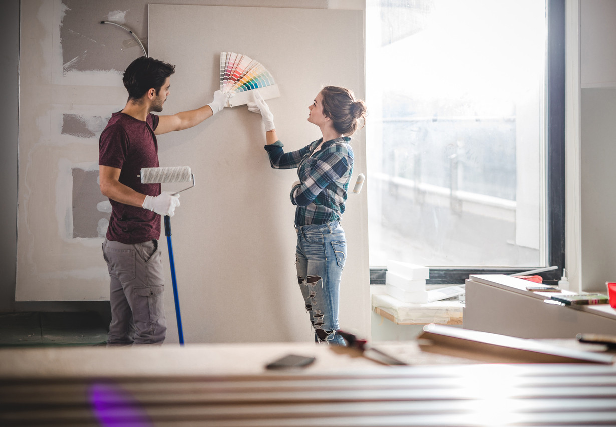 Young couple choosing the right color for their wall in new apartment.