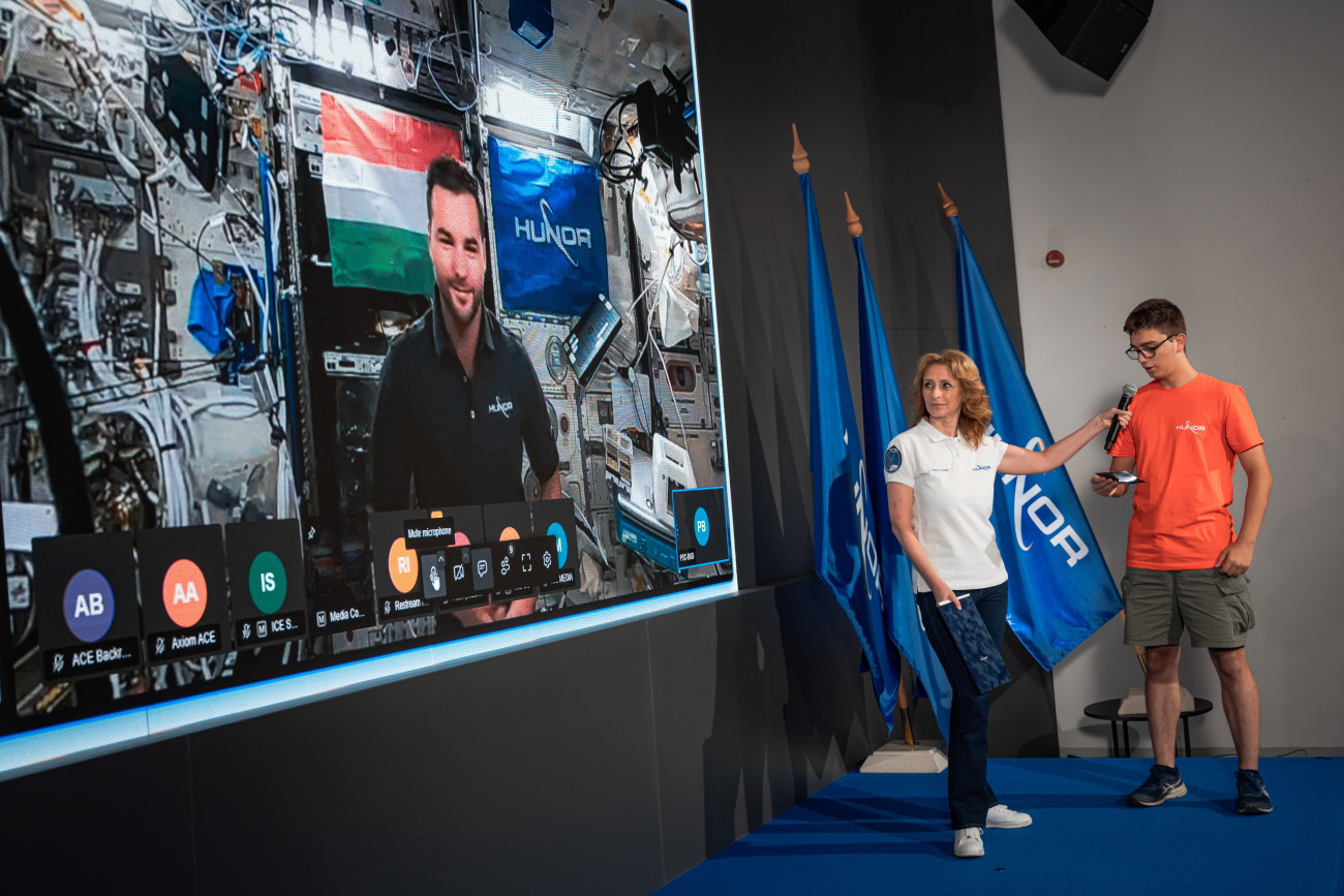 Budapest, 2025. július 2.
A HUNOR-program által közreadott képen az Országos Középiskolai Tanulmányi Verseny (OKTV) egyik győztes középiskolás diákja kérdést tesz fel élő beszélgetésben Kapu Tibornak, a Nemzetközi Űrállomáson (ISS) tartózkodó űrhajósnak Ferencz Orsolya űrkutatásért felelős miniszteri biztos, az esemény moderátorának társaságában a HUNIVERZUM Látogatóközpontban, a Millenárison 2025. július 2-án.
MTI/HUNOR