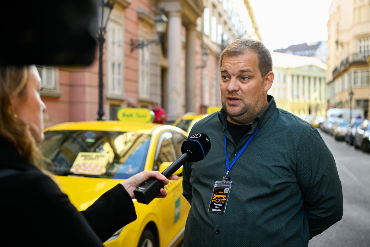 Budapest, 2025. október 29.
Váczi Norbert, a Fõvárosi taxi egyesület társelnöke nyilatkozik a sajtó képviselõinek taxisok tüntetésén a Fõvárosi Közgyûlés ülése alatt Városháza elõtt 2025. október 29-én. A taxisok tarifaemelést követelnek, valamint egyebek mellett szorgalmazzák az engedélyek számának korlátozását, az illegális fuvarszervezés felszámolását.
MTI/Purger Tamás