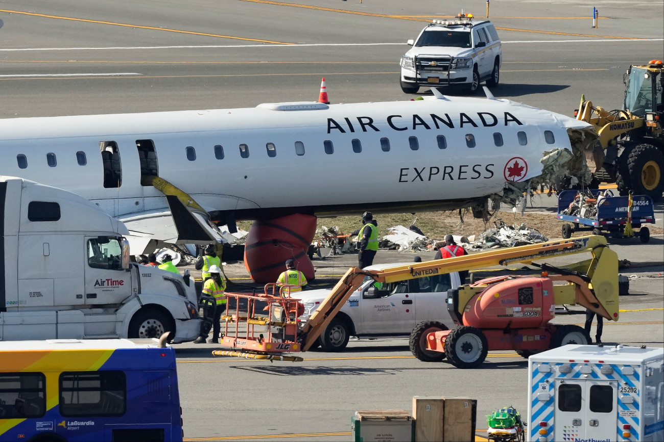 New York, 2026. március 25.
Szakértõk vizsgálják az Air Canada kanadai légitársaság repülõgépének roncsát 2026. március 25-én, három nappal azután, hogy 72 utassal és négyfõnyi személyzettel a fedélzetén leszállás után egy tûzoltóautónak ütközött a New York-i LaGuardia Repülõtéren. A balesetben a két pilóta életét vesztette, 41 embert keleltt kórházba vinni.
MTI/AP/Yuki Iwamura