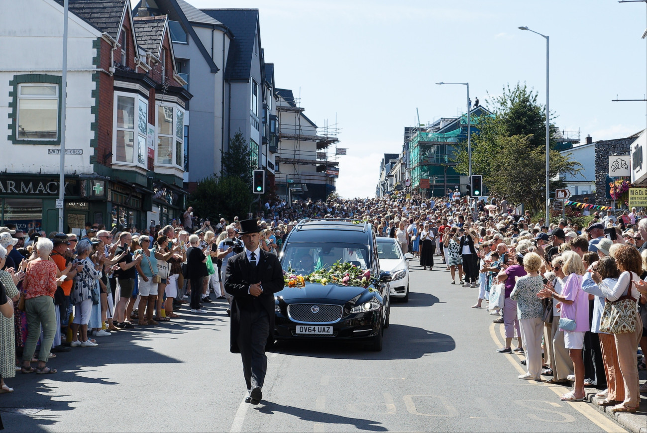 Mumbles, 2026. augusztus 15.
A Bonnie Tyler walesi énekesnõ koporsóját szállító jármû és gyászoló rajongók a Mumbles-ban rendezett búcsúztatásán 2026. augusztus 15-én. A Gaynor Hopkins néven született énekesnõ július 8-án, 75 éves korában hunyt el egy portugál kórházban.
MTI/EPA/Dimitris Legakis