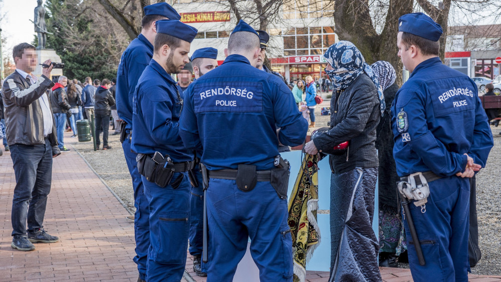Rendőrök igazoltatnak két embert, akik fejkendőben és csadorra hasonlító öltözékben jelentek meg Vona Gábor, a Jobbik elnöke és miniszterelnök-jelöltje orosházi utcafórumán 2018. március 13-án.