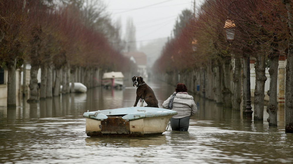 Villennes-sur-Seine, 2018. január 30.A medréből kilépett Szajna vizében gázolva szállítja csónakkal a kutyáját egy nő a Párizstól 30 kilométerre, nyugatra levő Villennes-sur-Seine településen 2018. január 30-án. A folyó az előző napon 5,85 méteren tetőzött a francia fővárosban, ahol a vízszint négy méterrel magasabb az átlagosnál. Az esőzések okozta ár levonulása hetekig eltarthat, a hajóközlekedés még legalább egy hétig szünetel a Szajnán. (MTI/EPA/Yoan Valat)