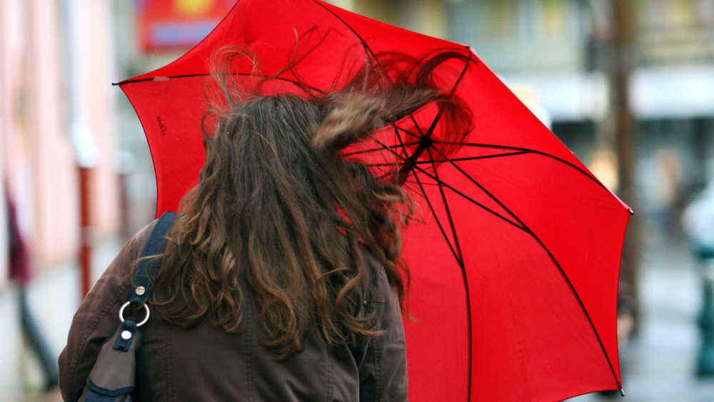 Szél fújja egy esernyővel kezében sétáló nő haját Nagykanizsán 2012. október 16-án.
