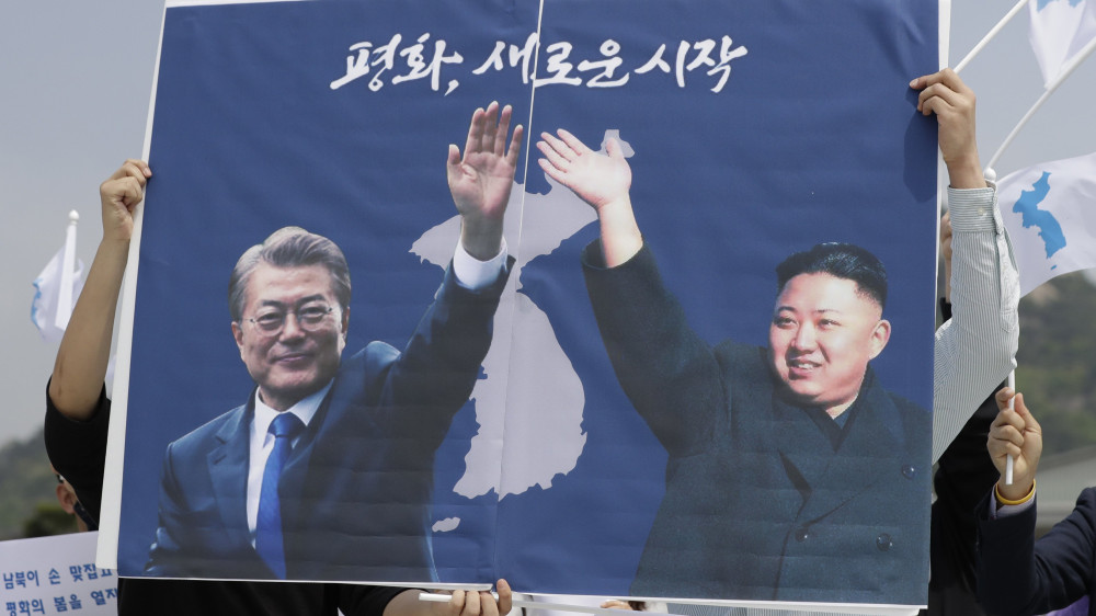 Szöul, 2018. április 26.A Korea-közi csúcstalálkozó sikerében bízó szimpatizánsok Mun Dzse In dél-koreai elnök (b) és Kim Dzsong Un észak-koreai vezető óriásplakátját emelik a magasba a szöuli elnöki rezidencia, a Kék Ház előtt 2018. április 26-án. A két politikus másnap az országaikat elválasztó betonakadályoknál találkozik, majd a dél-koreai díszőrség kíséri őket a tárgyalások helyszíneként szolgáló Panmindzson határfaluba a fogadási ceremóniára. Kim Dzsong Un személyében 65 éve először lép észak-koreai vezető dél-koreai területre. (MTI/AP/Li Dzsin Man)