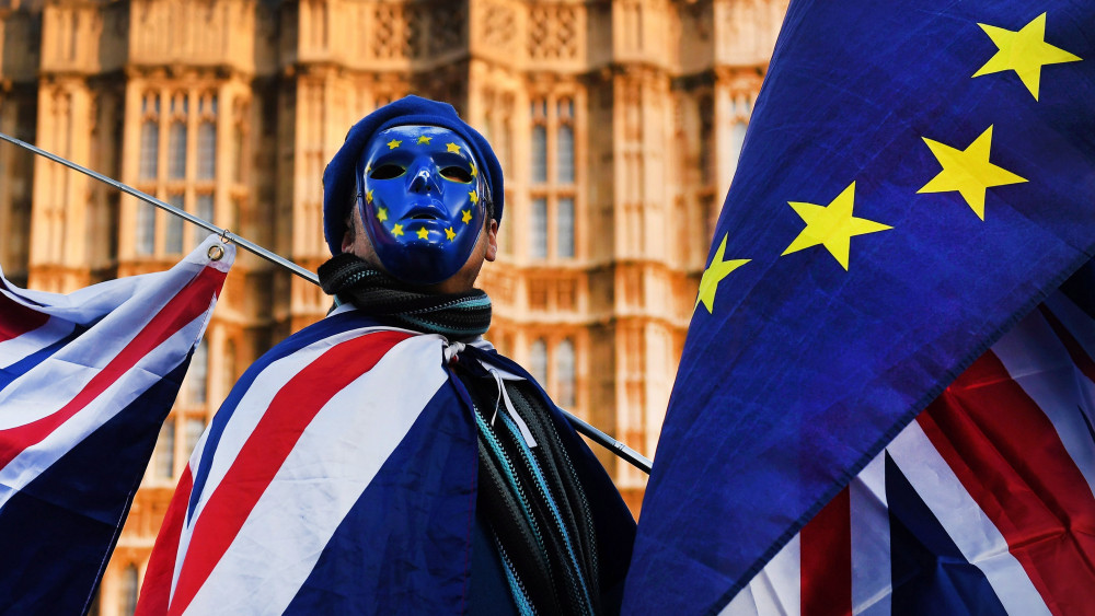 London, 2017. december 18.A Nagy-Britannia EU-ból való kilépését ellenző tüntetők egyike a brit (b) és az uniós zászlóval a brit parlament épülete előtt tartott tüntetésen 2017. december 18-án. Theresa May ezen a napon számol be a londoni alsóház képviselőinek a brüsszeli EU-csúcsról, amelyen az unióban maradó tagállamok állam- és kormányfői úgy döntöttek, hogy el lehet kezdeni a brit EU-tagság megszűnéséről folyó tárgyalássorozat második szakaszát. (MTI/EPA/Andy Rain)