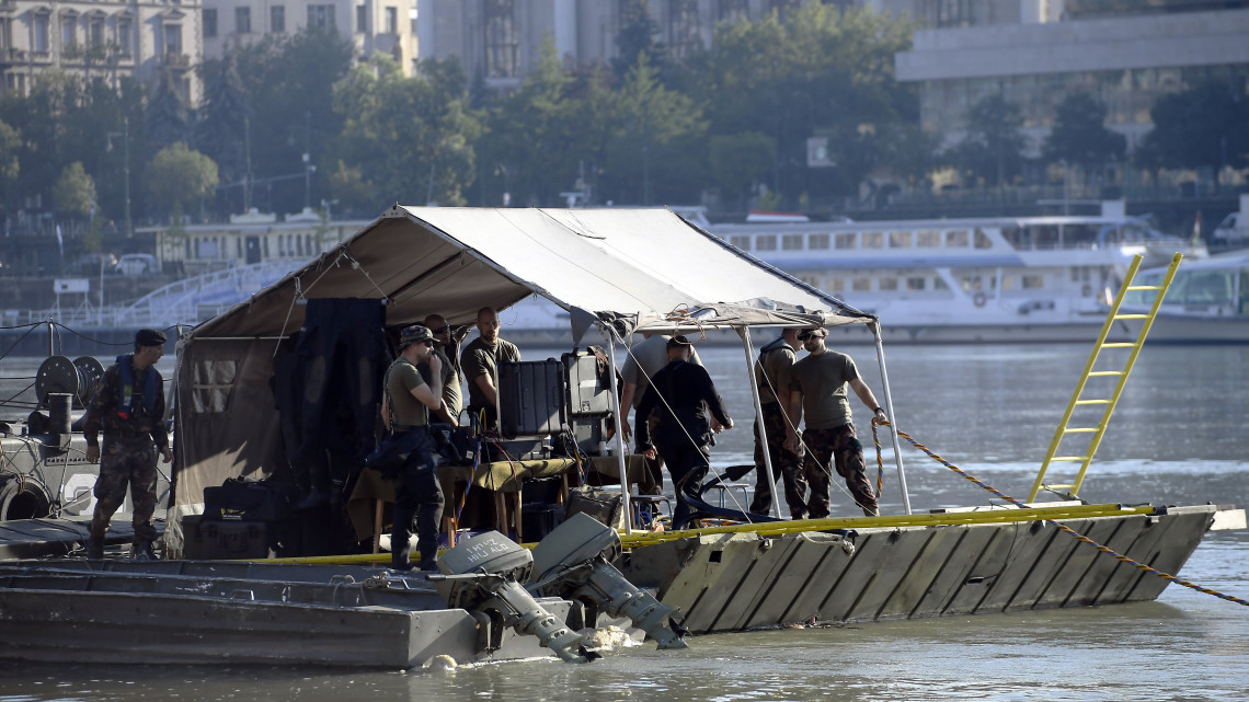 Tűzszerészek előkészítik az Erzsébet-hídnál talált világháborús robbanótest kiemelését egy honvédségi hajóhoz kapcsolt pontonhíd-elemről 2018. július 5-én. A bombáról korábban egy balesetnél segédkező civil búvárcsoport tagjai tettek bejelentést a rendőrségen.
