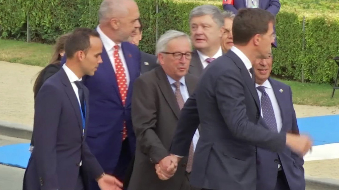 Brüsszel, 2018. július 12.Videofelvételről készített kép, amelyen Jean-Claude Junckert, az Európai Bizottság elnökét (k) Mark Rutte holland miniszterelnök segíti a Cinquantenaire Parkban a NATO kétnapos brüsszeli csúcsértekezletének első napján, 2018. július 11-én. Junckert többször botladozni, furcsán menni, egyensúlyát veszíteni látták a díszvacsora előtt. Az elnök korábban azt mondta, isiászban szenved, és ez olykor kihat a mozgására. (MTI/AP)