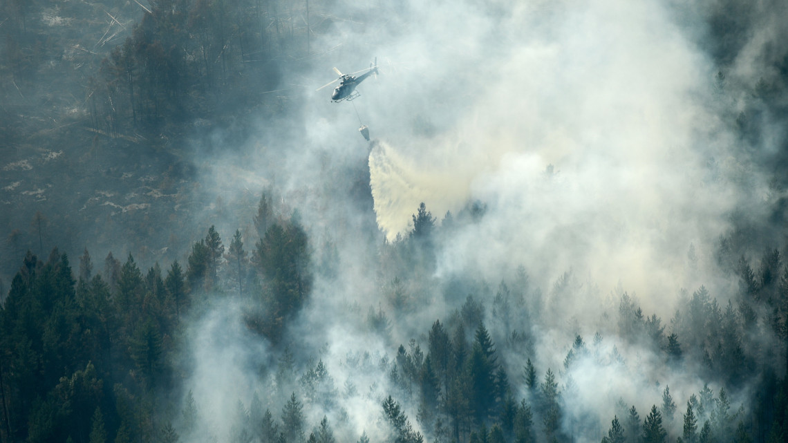Ljusdal, 2018. július 19.Erdőtüzet oltanak helikopterről a svédországi Ljusdal település közelében 2018. július 18-án. A szokatlan szárazság sújtotta skandináv államban napok óta harcolnak a lángokkal, eddig a tűzfészkek felét, mintegy negyvenet sikerült eloltani. (MTI/EPA/Maja Suslin)